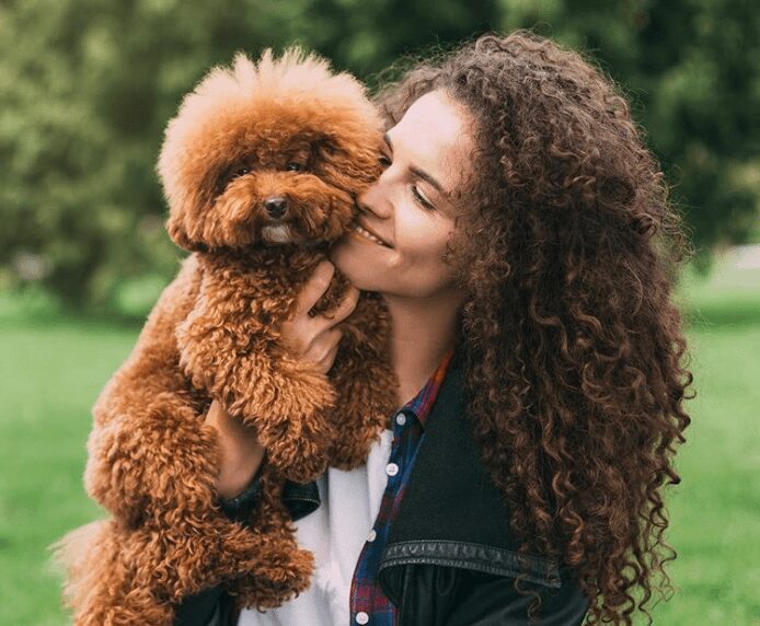 A fluffy dog being held by a woman in a park