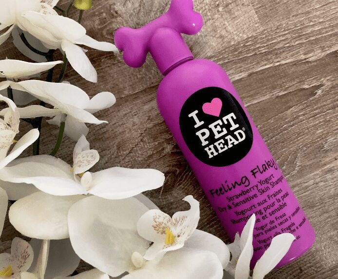 A bottle of Pet Head Feeling Flaky next to some flowers