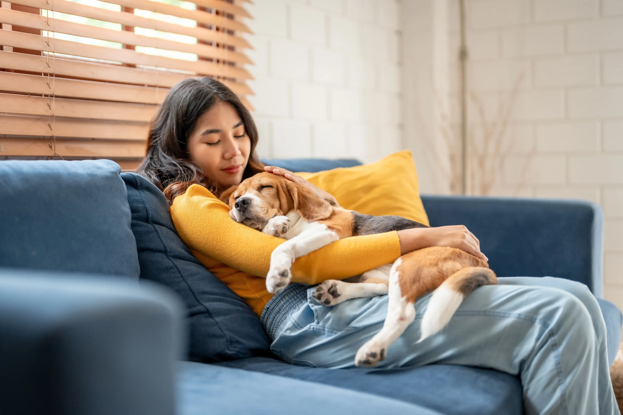 Woman relaxing on a sofa while cuddling a sleeping puppy in her arms
